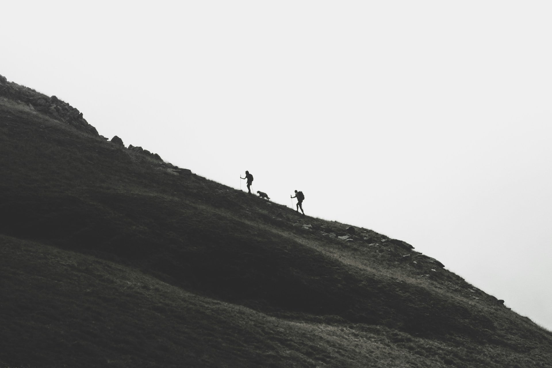 Epic mountain adventure landscape with hikers exploring alpine trails under dramatic peaks and blue sky