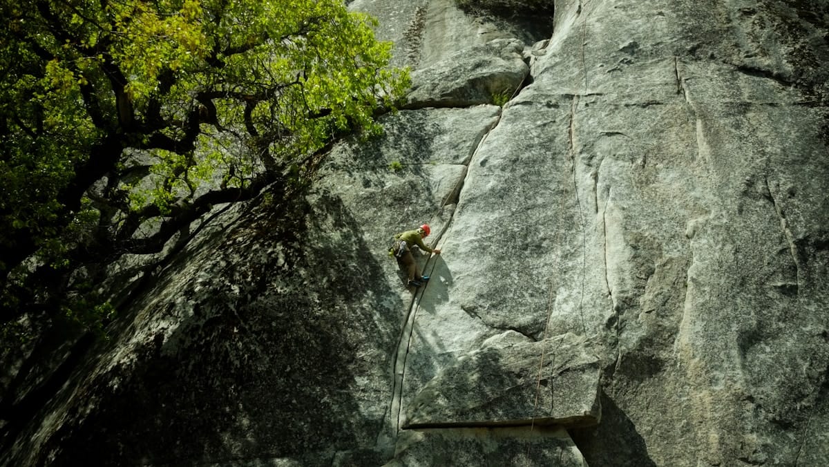 Professional rock climbing in Yosemite with safety equipment and gear, demonstrating secure adventure travel practices